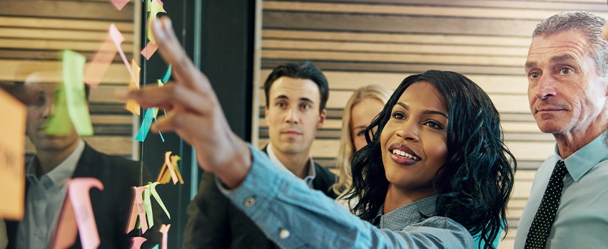 employees looking at a board with sticky notes