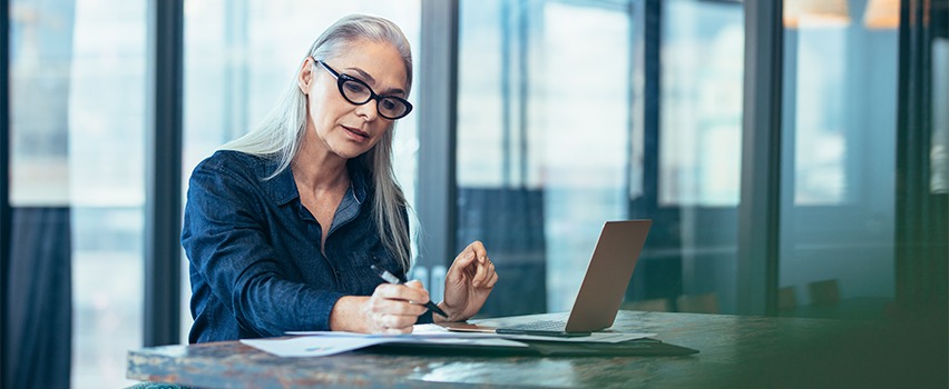 woman taking notes at while sitting at her computer